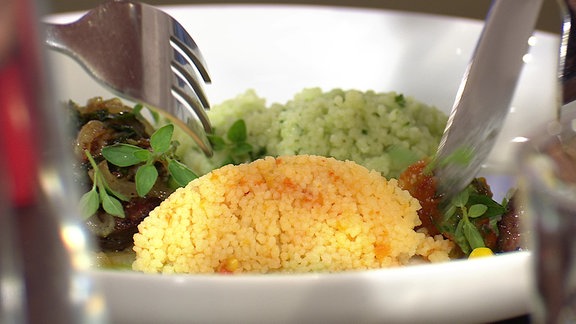 Ein angerichteter Teller mit Couscous in zwei Farben und angebratener Leber.