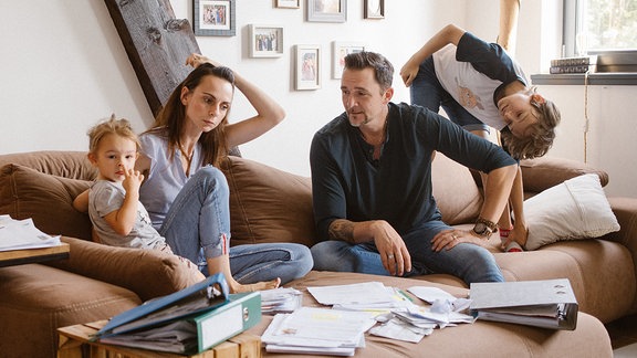 Momentaufnahme einer Familie, die auf einem Sofa sitzt.