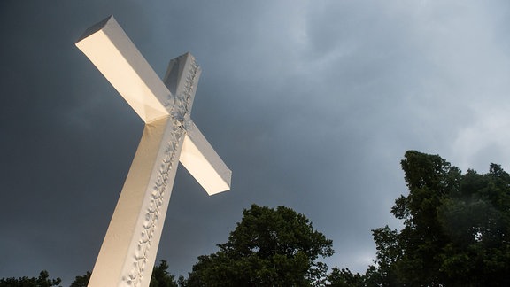 Dunkle Wolken ziehen über einem Kreuz auf