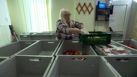 Eine Frau sortiert Lebensmittel in Kisten ein.