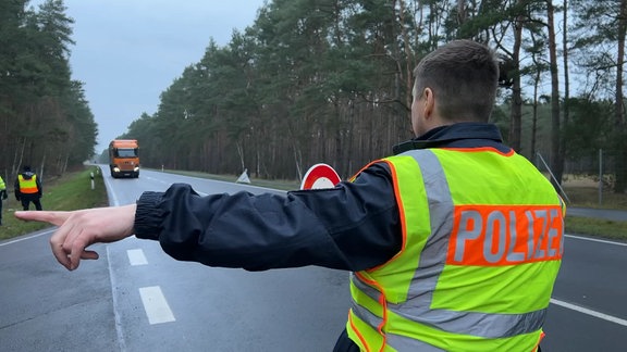 Ein Polizist winkt einen Lkw an die Seite.