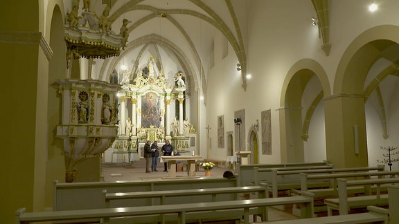 Personen stehen im Innenraum einer Kirche.