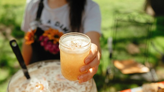 Eine Hand hält ein Glas mit Bowle.