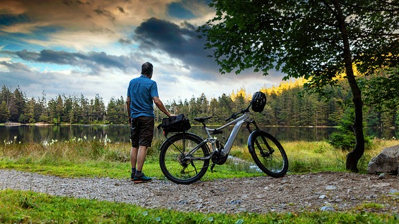 Ein Radtourist genießt die Abendstimmung am Feldsee im Schwarzwald 