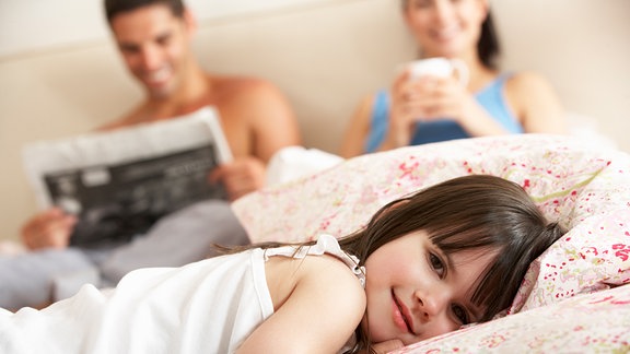 Familie entspannt gemeinsam im Bett