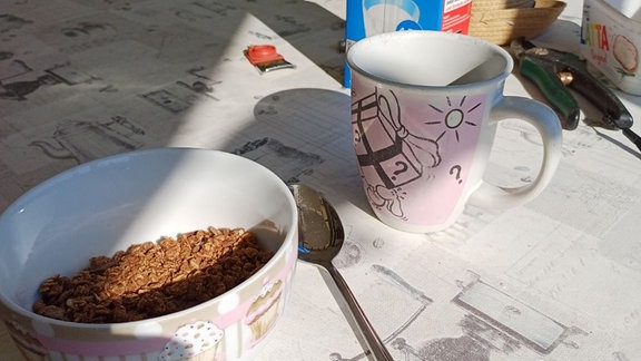 Müslischüssel und Tasse auf Frühstückstisch