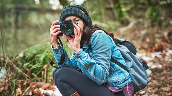 Junge Frau mit Kamera im Wald.