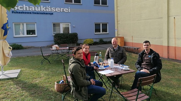 Vier Menschen am Tisch im Garten einer Schaukäserei