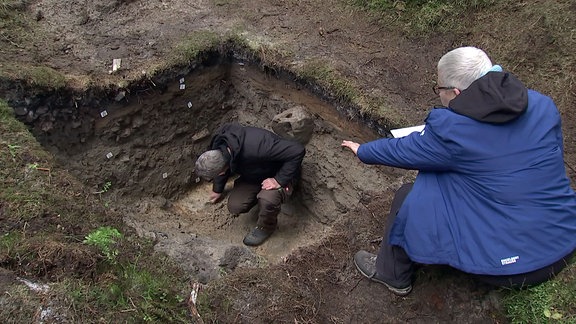 Archeologen bei Augrabungen in einem Wald.