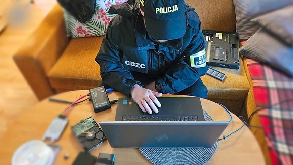 Ein Polizist sichert Daten auf einem Laptop