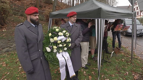 Zwei Soldaten halten einen Kranz