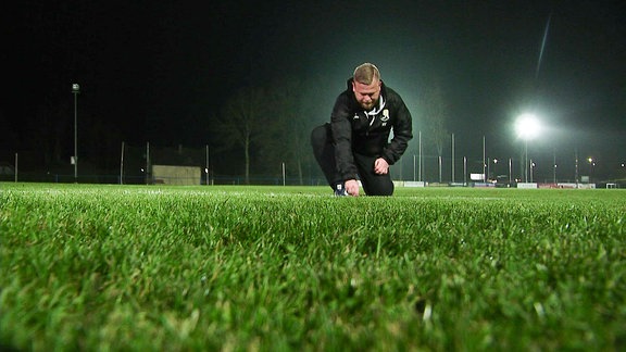 Ein Mann pflegt einen Fußballrasen