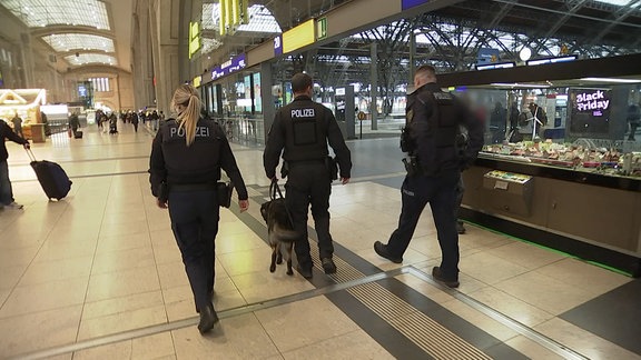 Polizeieinsatzkräfte gehen durch den Bahnhof. 