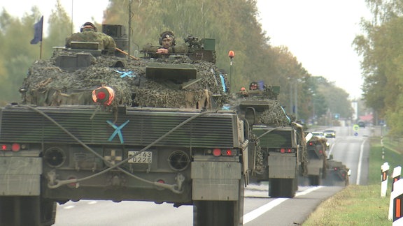 Mehrere Panzer fahren auf einer Landstraße im Frühherbst.