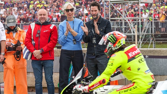 Keanu Reeves und Alexandra Grant beim Liqui Moly Motorrad Grand Prix Deutschland 2024 auf dem Sachsenring am 07.07.24.