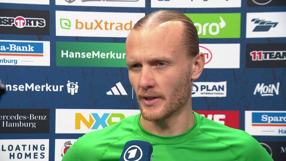 Spieler im Interview vor Werbebande