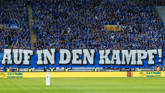 Eine gefüllte Fantribüne des 1. FC Magdeburg mit Transparenten