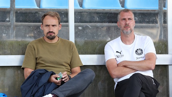  Toni Wachsmuth (l., Lok Leipzig, Geschaeftsfuehrer) und Jochen Seitz (Lok Leipzig, Trainer) sitzen auf einer Bank.