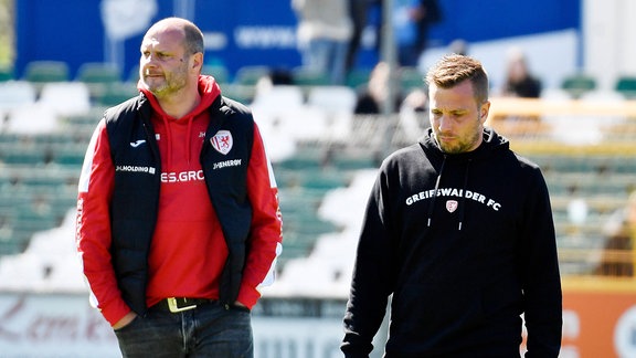 David Wagner (Geschaeftsfuehrer Greifswald) (li.) und Lars Fuchs (Trainer Greifswald) laufen im Stadion nebeneinander.