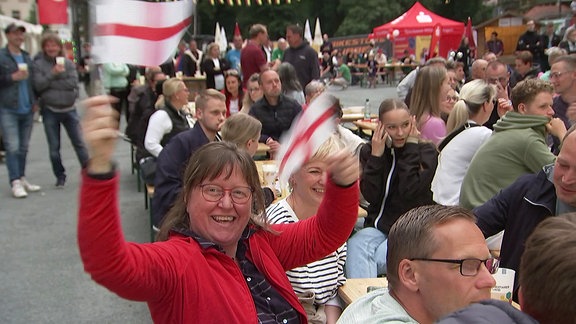 Blick auf die Fanmeile mit Fähnchenschwinkender Frau