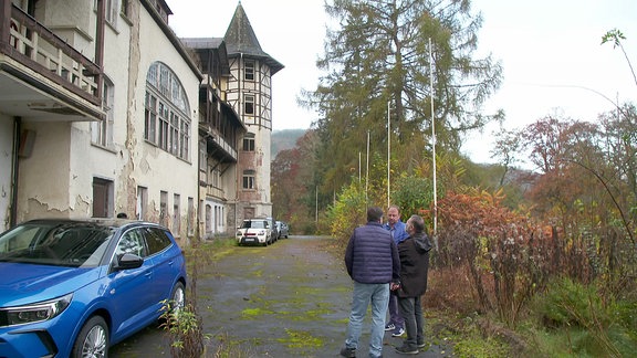 Drei Männer stehen vor einem alten Gebäude