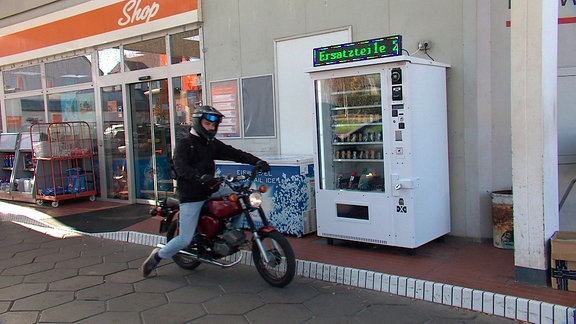 Mopedfahrer vor Ersatzteil-Automat