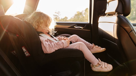 Ein Mädchen sitz in einem Kindersitz im Auto.