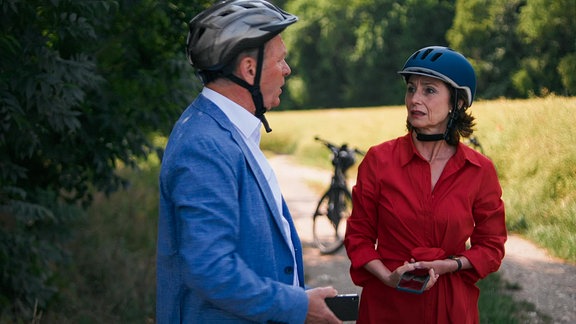 Ein Mann und eine Frau mit  Fahradhelmen auf einem Feldweg.