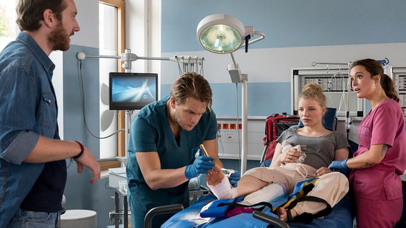 Zwei Frauen und zwei Männer in einem Krankenzimmer.