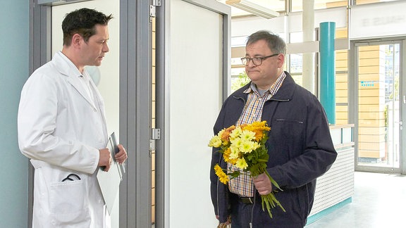 Dr. Philipp Brentano (Thomas Koch, li.) hat Hans-Peter Brenner (Michael Trischan, re.) mit der Betreuung einer hartnäckigen Patientin beauftragt. Wenn es einer schafft, dann er. Doch als Philipp Hans-Peter mit Blumen und Äpfeln sieht, die Hans-Peter aus dem Garten der Patientin geholt hat, muss er dem Ganzen eine Grenze setzen: Philipp ordnet an, dass Hans-Peter wieder auf berufliche Distanz gehen soll.