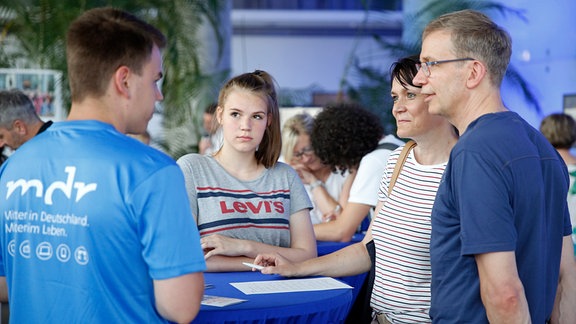 Ein junger Mann und eine junge Frau unterhalten sich mit einem Ehepaar.