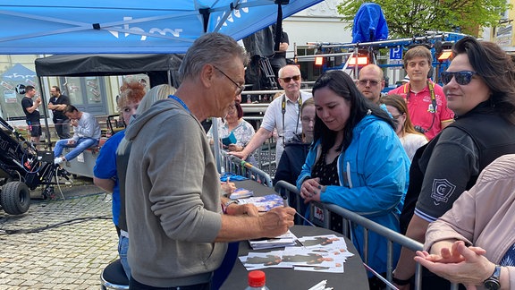 Olaf Berger (l.) im Autogrammkartenzelt