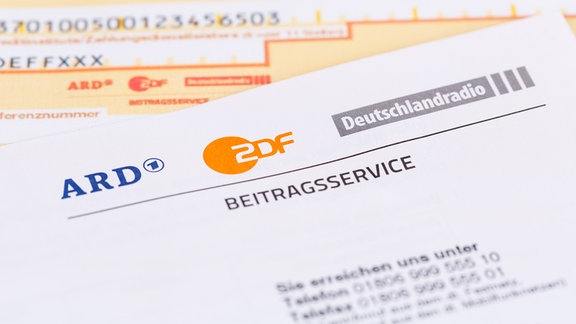 Ein Schreiben vom ARD/ZDF-Beitragsservice liegt auf einem Überweisungsträger.