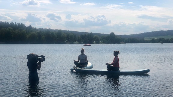 Zwei Menschen beim Yoga auf Surfbrettern auf dem Stausee Hohenfelden