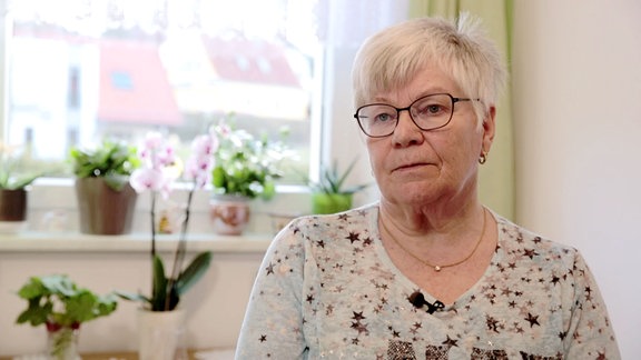 Frau Hertam sitzt in ihrer Stube nahe dem Fenster.