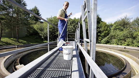 Klärwärter nimmt in der Kläranlage eine Wasserprobe.