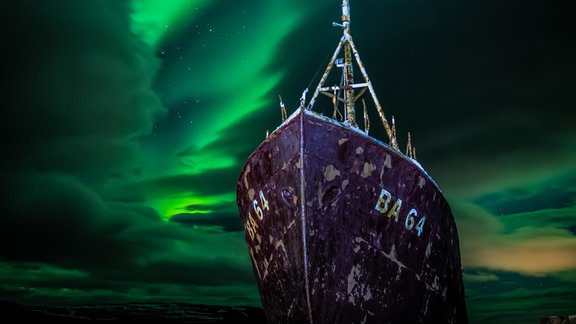 Kategorie: Polarlichter  Eine isländische Saga © Carl Gallagher  Der Fotograf begab sich auf eine neuntägige, 2500 Meilen lange Reise durch die Wolken, um die Aurora Borealis über dem Wrack der Gardur in den Westfjorden Islands einzufangen.   Aufgenommen mit der Canon 6D Mark II Kamera, 24mm f/2, ISO 400, 10 Sekunden Belichtungszeit  Standort: Patreksfjörður, Westfjorde, Island 