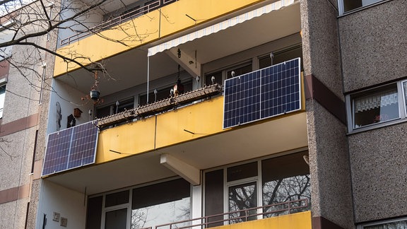 Zwei Solarpaneele an einer Balkonbrüstung eines eingelassenen Balkons in einem Plattenbau