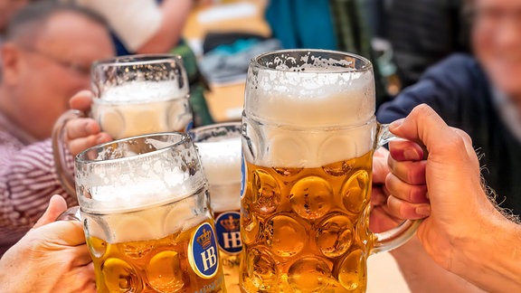 Wiesnbesucher stoßen im mit ihrer Maß Bier an.