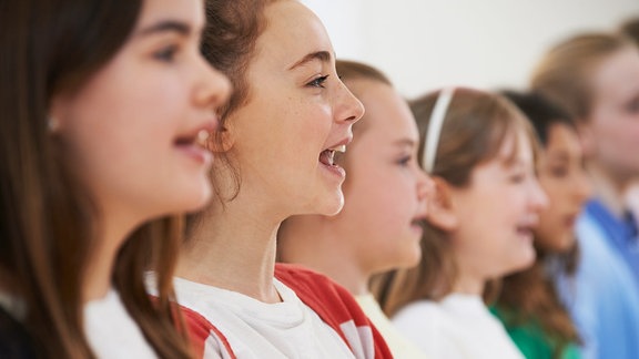 Drei hellhäutige Mädchen stehen nebeneinander und singen