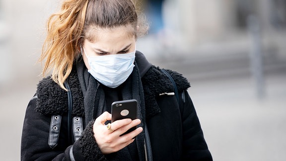 Eine Frau blickt auf ihr Smartphone.