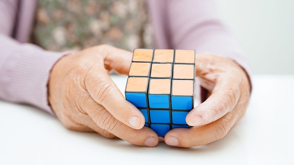 Ein Zauberwürfel bzw. "Rubik’s Cube" in den Händen einer älteren Person