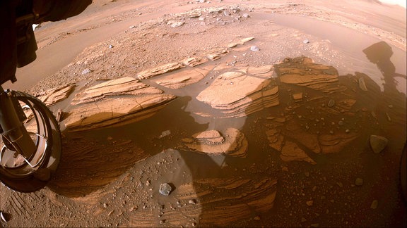 Fotografie des Perseverance Rovers der Masgegend "Enchanted Lake" mit roten Felsen und Staub am Boden.