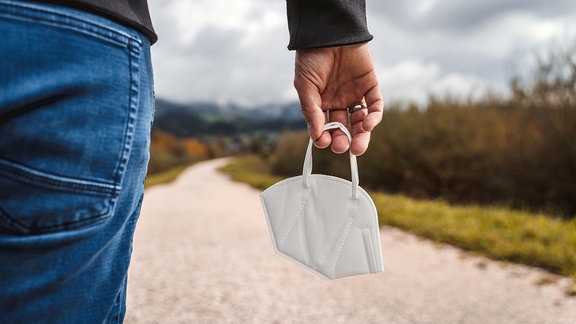 Maske in der Hand bei einem Herbst Spaziergang. 