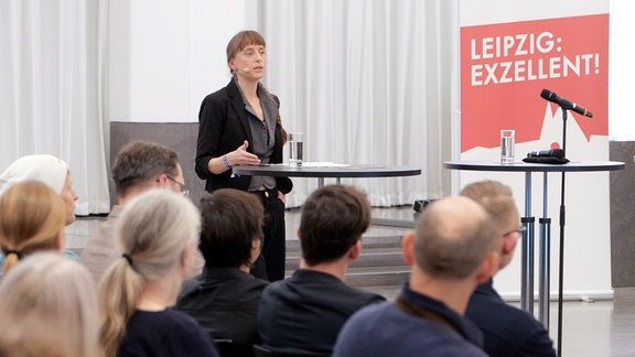 Die Physikerin Friederike Otto trägt ein Headsetmikrofon und spricht in der Universität Leipzig vor Publikum.