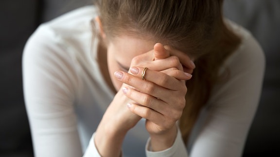 Eine Frau stützt sich auf Ihre Hände und denkt nach