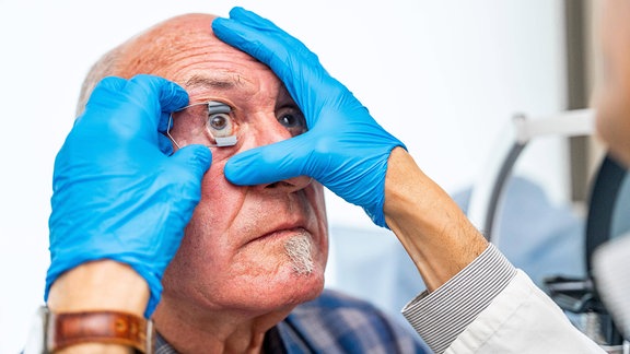 Augenarzt öffnet das Auge eines Patienten