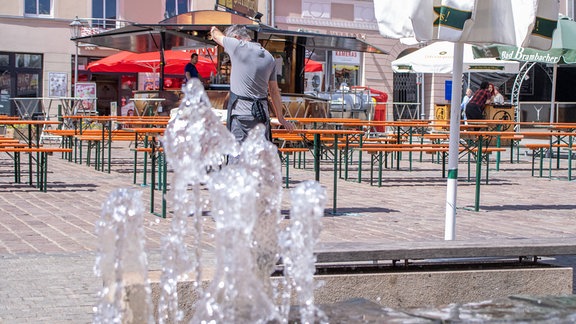 Springbrunnen vor einem Freisitz. Schwitzender Kellner.