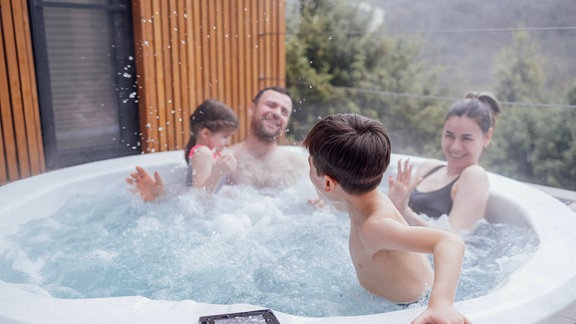 Eine Familie sitzt im Whirlpool.