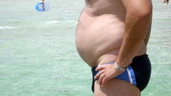 Mann mit Bierbauch am Strand